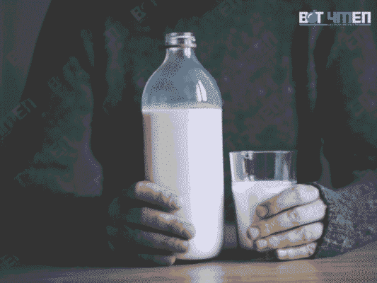 Một bạn nam đang cầm trên tay một cái cốc có sữa đậu nành và một chai sữa đậu nành 
